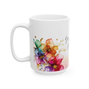 May include: White ceramic mug with a colorful floral design and gold accents. The text "You are beautiful" is printed on the mug.