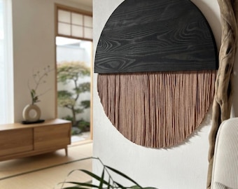 Può includere: Una decorazione da parete circolare con la metà superiore in legno tinto scuro con venature visibili e la metà inferiore composta da numerosi fili verticali color marrone chiaro che creano un aspetto testurizzato a frange.
