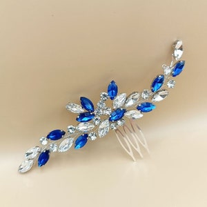 May include: A silver hair comb with blue and clear crystal rhinestones arranged in a floral design.