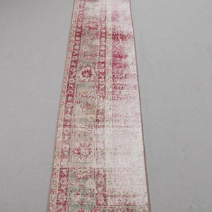 Pode incluir: Um tapete corredor vintage vermelho e creme com um padrão floral desbotado. O tapete tem um aspecto desgastado e é feito de lã.