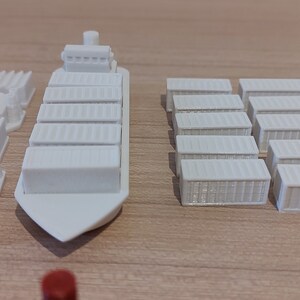 May include: A white cargo ship with a white container on top. There are multiple white containers on the table, as well as a group of yellow containers.
