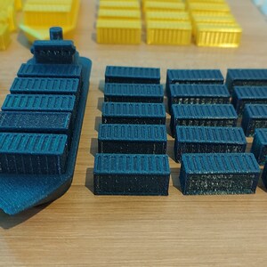 May include: A blue toy cargo ship with a row of blue toy shipping containers behind it. There are also stacks of red and yellow toy containers.