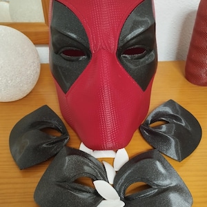 Può includere: Una maschera di Deadpool rossa e nera con pezzi per gli occhi abbinati e denti bianchi. La maschera è una copertura completa della testa con ritagli neri per gli occhi. I pezzi per gli occhi sono neri con una lucentezza argentata. I denti sono bianchi.