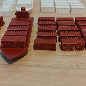 May include: A red cargo ship with a row of containers on deck, along with a collection of red, blue, white, and yellow containers.