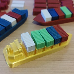 May include: A yellow toy cargo ship with six colourful containers. The containers are green, blue and red. The ship is made of plastic and has a flat bottom.
