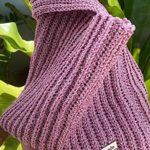 May include: A pink crocheted bag with a silver tag that says "handmade".
