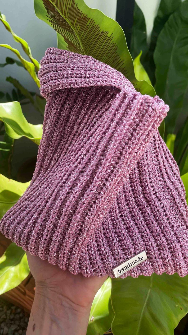 May include: A pink crocheted bag with a silver tag that says "handmade".