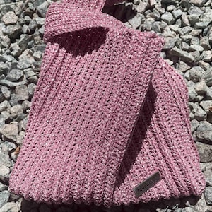 May include: A pink crocheted bag with a silver tag that says "handmade".
