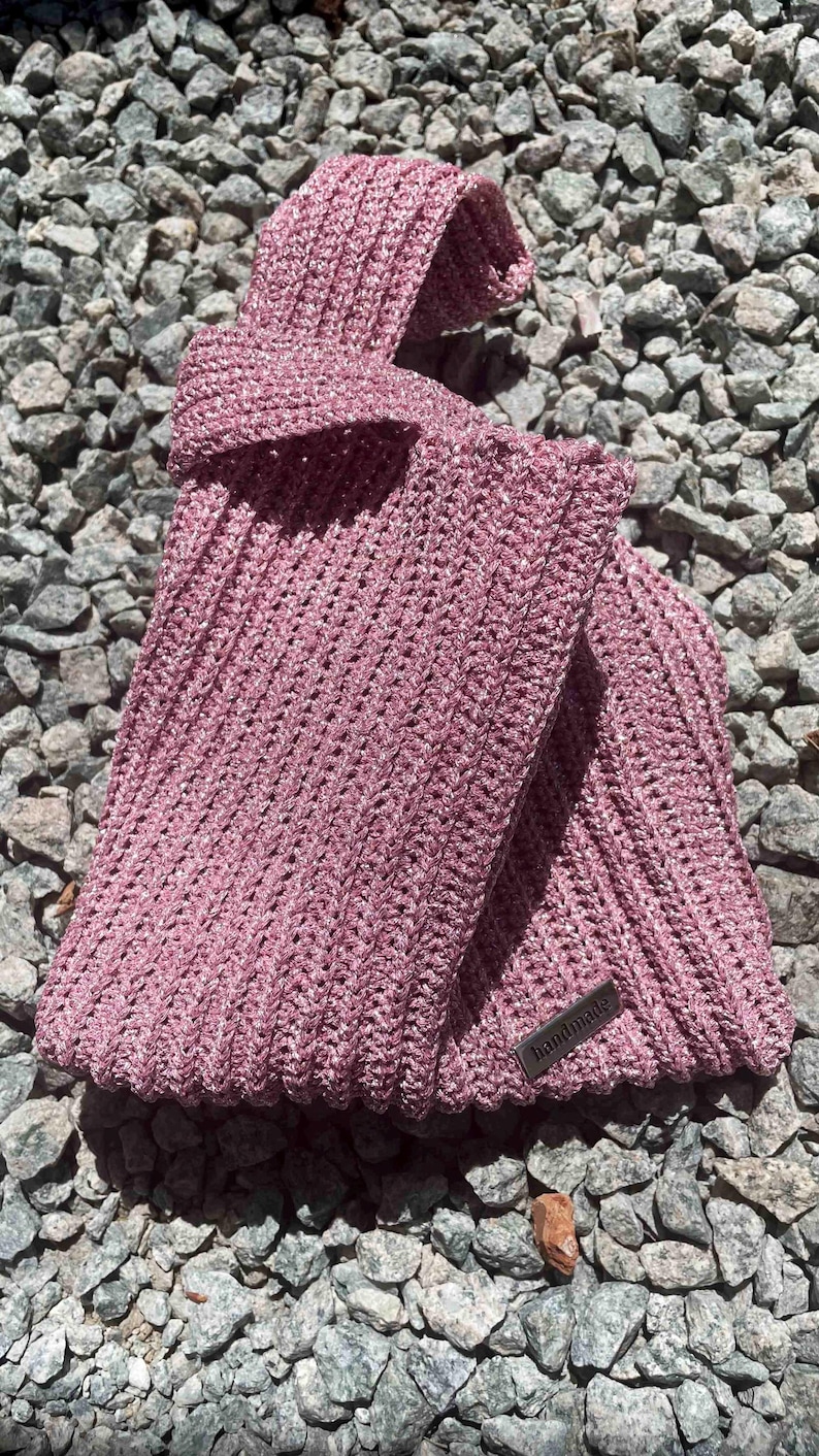 May include: A pink crocheted bag with a silver tag that says "handmade".