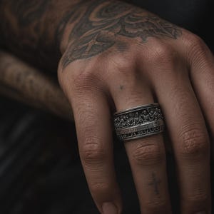 Può includere: Un anello d'argento con un rilievo dettagliato raffigurante una scena religiosa. L'anello è indossato su un dito, mettendo in risalto il design intricato. Il design dell'anello è una caratteristica prominente.