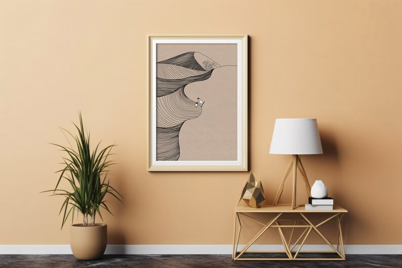 May include: A framed black and white line drawing of a surfer riding a wave. The drawing is on a beige background and is framed in a light wood frame. The frame is hanging on a light orange wall.
