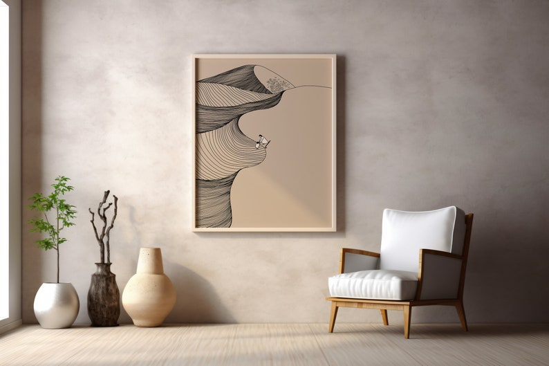May include: A framed black and white line drawing of a desert landscape with a person standing on a dune. The drawing is on a beige background and is framed in a light wood frame.