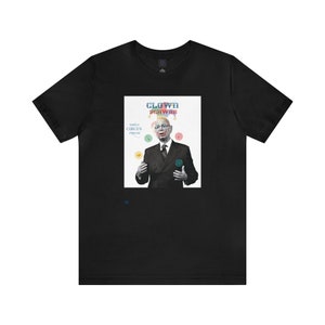 May include: Black t-shirt with a white graphic of a man in a suit with a clown nose and hat. The graphic says "Clown Schwab" and "World Circus Forum".