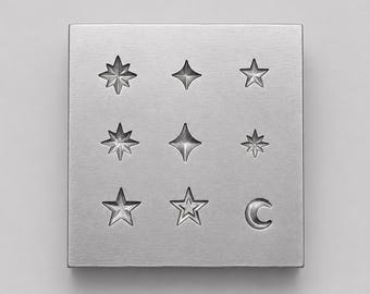 May include: A square silver metal stamping block featuring a grid of nine engraved celestial symbols. The design includes various star shapes, including eight-pointed, four-pointed, and five-pointed stars, along with a single crescent moon symbol.