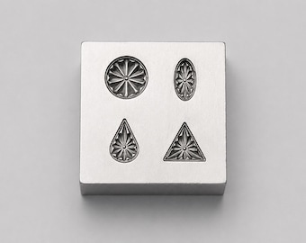 May include: A square silver-toned metal block featuring four recessed impressions with intricate starburst patterns. The shapes include a circle, an oval, a teardrop, and a triangle, each centered with a small dot and radiating lines.