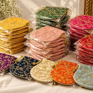 May include: A collection of small, square fabric pouches with rounded corners, each featuring intricate gold floral embroidery and a drawstring closure. The pouches are available in various colors including yellow, pink, green, red, purple, blue, and orange.