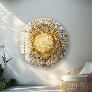 May include: Circular wall art with a gold and silver abstract design. The artwork is made of many small, textured pieces. The piece is mounted on a white wall, and the scene is outdoors. The artwork is approximately 76 cm in diameter.