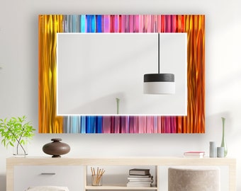 May include: A rectangular mirror with a colorful, striped frame. The frame is made of glass and features a variety of colors, including red, orange, yellow, green, blue, and purple. The mirror is hanging on a white wall above a wooden shelf.