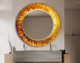 May include: A round gold mirror with a textured, sunburst design hangs above a wooden vanity with a grey countertop.