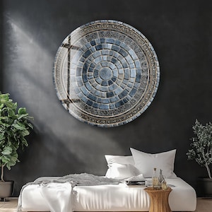 Może przedstawiać: Duże, okrągłe dzieło sztuki ściennej z mozaikowym wzorem w odcieniach niebieskiego i szarego. Grafika ma okrągły wzór z dekoracyjną obwódką. Jest zamontowana na ciemnoszarej ścianie nad białym łóżkiem.