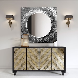 a black and gold sideboard with a round mirror above it