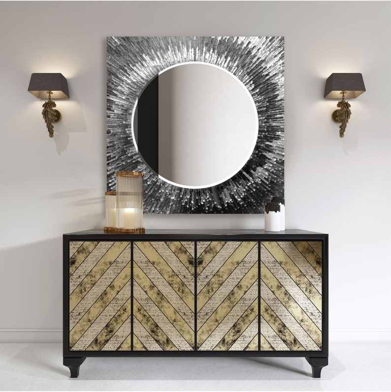 a black and gold sideboard with a round mirror above it