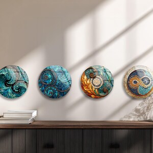 four circular wall art pieces with unique designs, displayed on a wall above a wooden shelf with books and a vase.
