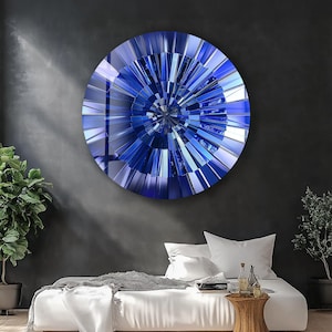 Könnte beinhalten: Ein großes, rundes Wandkunstwerk mit einem auffälligen blau-silbernen geometrischen Design. Das Kunstwerk zeigt ein radiales Muster aus abgewinkelten Segmenten, das einen dynamischen, auffälligen visuellen Effekt erzeugt. Das Stück ist an einer dunkelgrauen Wand befestigt.