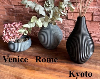 May include: Three black ceramic vases with a ribbed texture. The vases are labeled "Venice", "Rome", and "Kyoto".