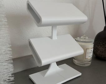 May include: White two-tiered stand with a rounded rectangular top and a base. The stand is made of plastic and has a modern design.