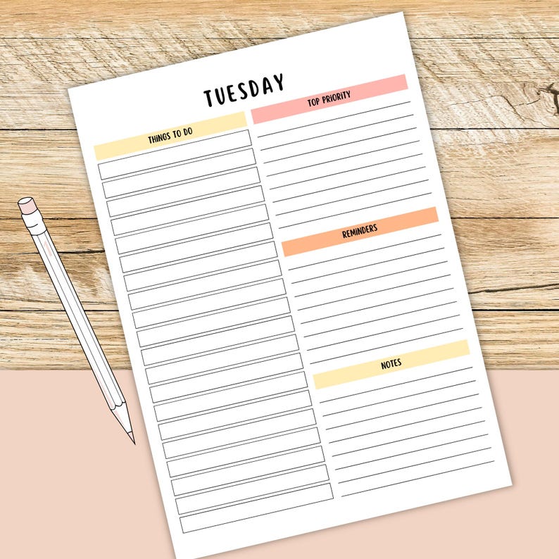 May include: A white paper planner for Tuesday with sections for things to do, top priority, reminders, and notes. The planner has a light pink and yellow color scheme. A white pencil with a pink eraser rests on the planner.