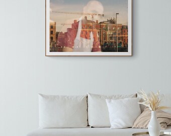 May include: A framed photograph of a city skyline with a crane in the background. The image is taken from a window, and the reflection of a person is visible in the glass.