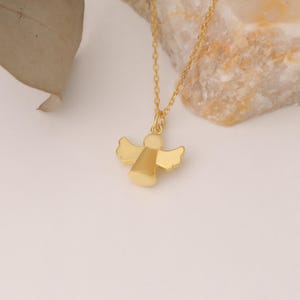 May include: A gold angel pendant necklace. The angel is a simple design with wings and a body.