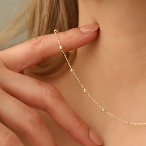 May include: A delicate gold necklace with small, round beads. The necklace is simple and elegant, perfect for everyday wear.