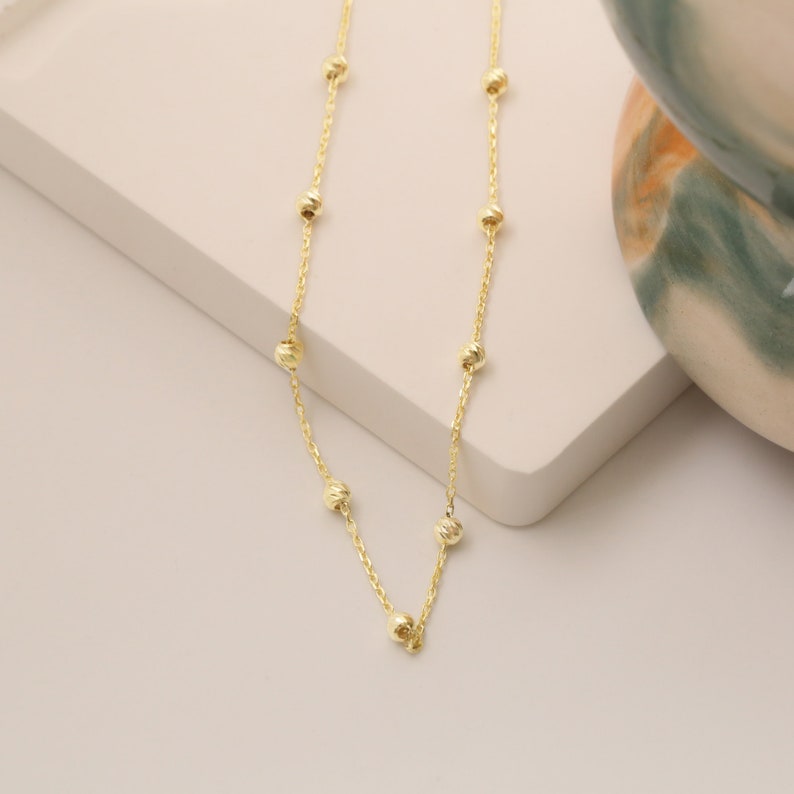 May include: A gold chain necklace with small round beads.