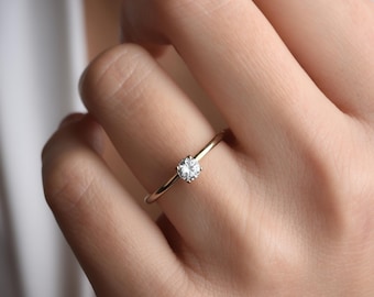 May include: A simple gold band ring with a single round diamond in the center.