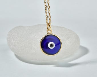 May include: A gold chain necklace with a blue and white evil eye pendant. The pendant is round and has a gold rim.