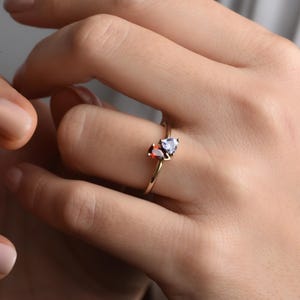 Peut inclure: Une bague en or avec deux pierres précieuses en forme de poire. La plus grande pierre est rouge et la plus petite est bleue.