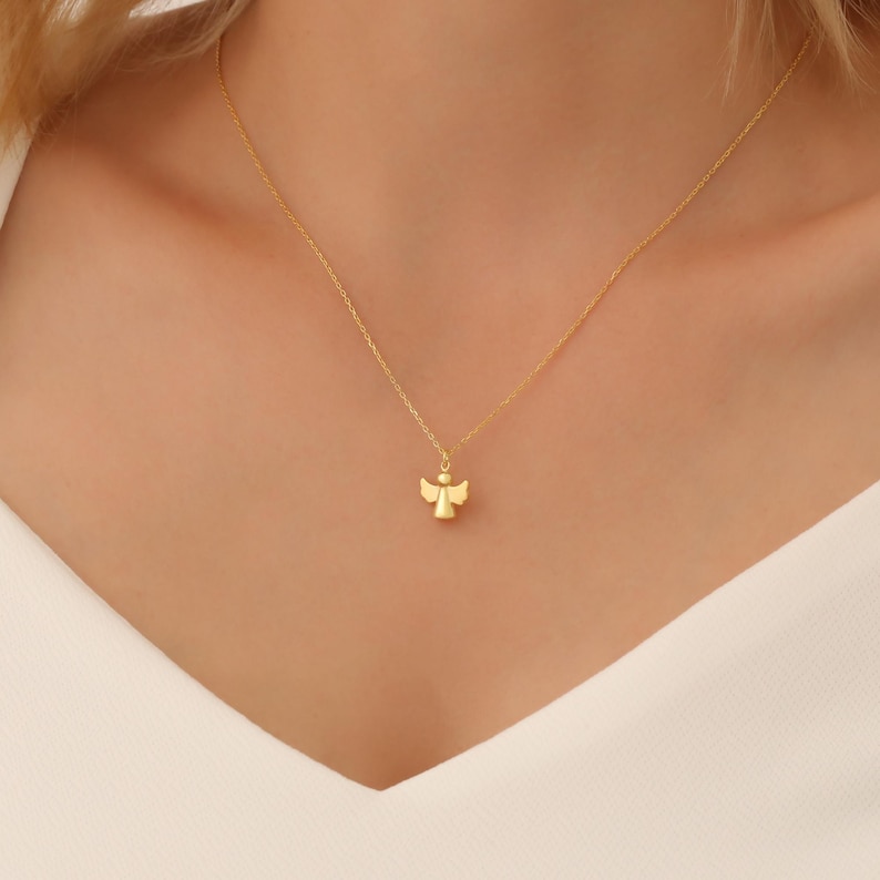 May include: A gold chain necklace with a small angel pendant.
