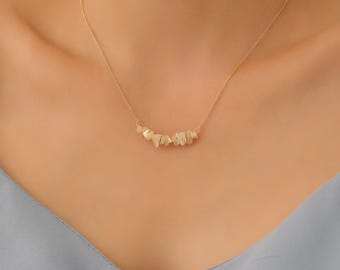 May include: A gold chain necklace with a delicate row of small, irregular, off-white stones.