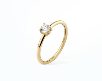 May include: A simple gold band ring with a single, round, clear diamond.