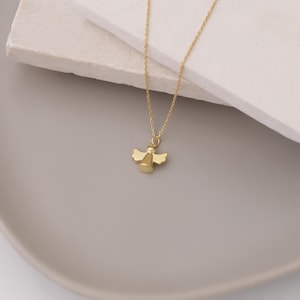 May include: A gold angel pendant necklace. The angel is a simple design with wings and a halo.