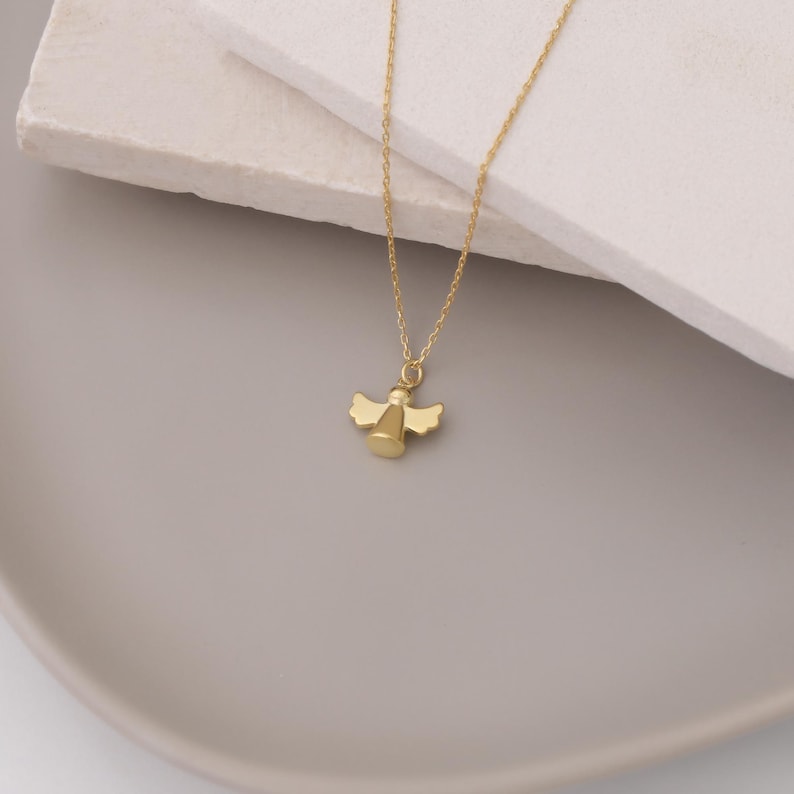 May include: A gold angel pendant necklace. The angel is a simple design with wings and a halo.