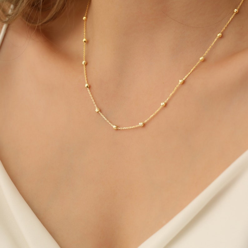 May include: A delicate gold chain necklace with small round beads.