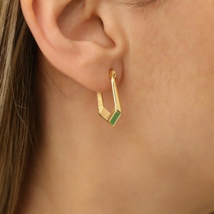 Op de afbeelding: Gouden creolen met een groen geometrisch ontwerp.