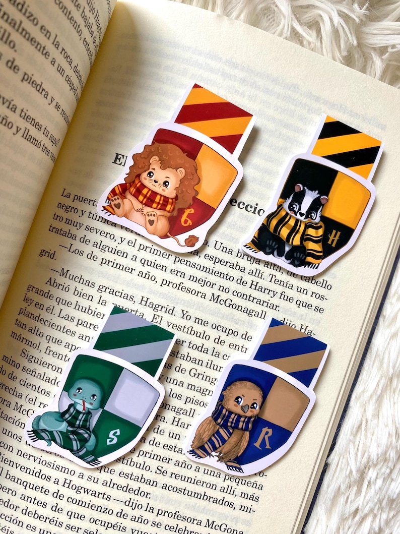 May include: Four colorful bookmarks featuring the Hogwarts house crests with cute animal illustrations. The crests are Gryffindor, Hufflepuff, Slytherin, and Ravenclaw. Each bookmark has a different animal: a lion, a badger, a snake, and an owl.