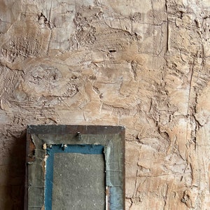 Può includere: Una cornice per foto in legno vintage con finitura marrone scuro e un passepartout blu e grigio. La cornice è leggermente danneggiata e ha un aspetto usurato.
