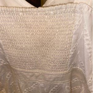 May include: White cotton dress with a white lace overlay and a smocked bodice.