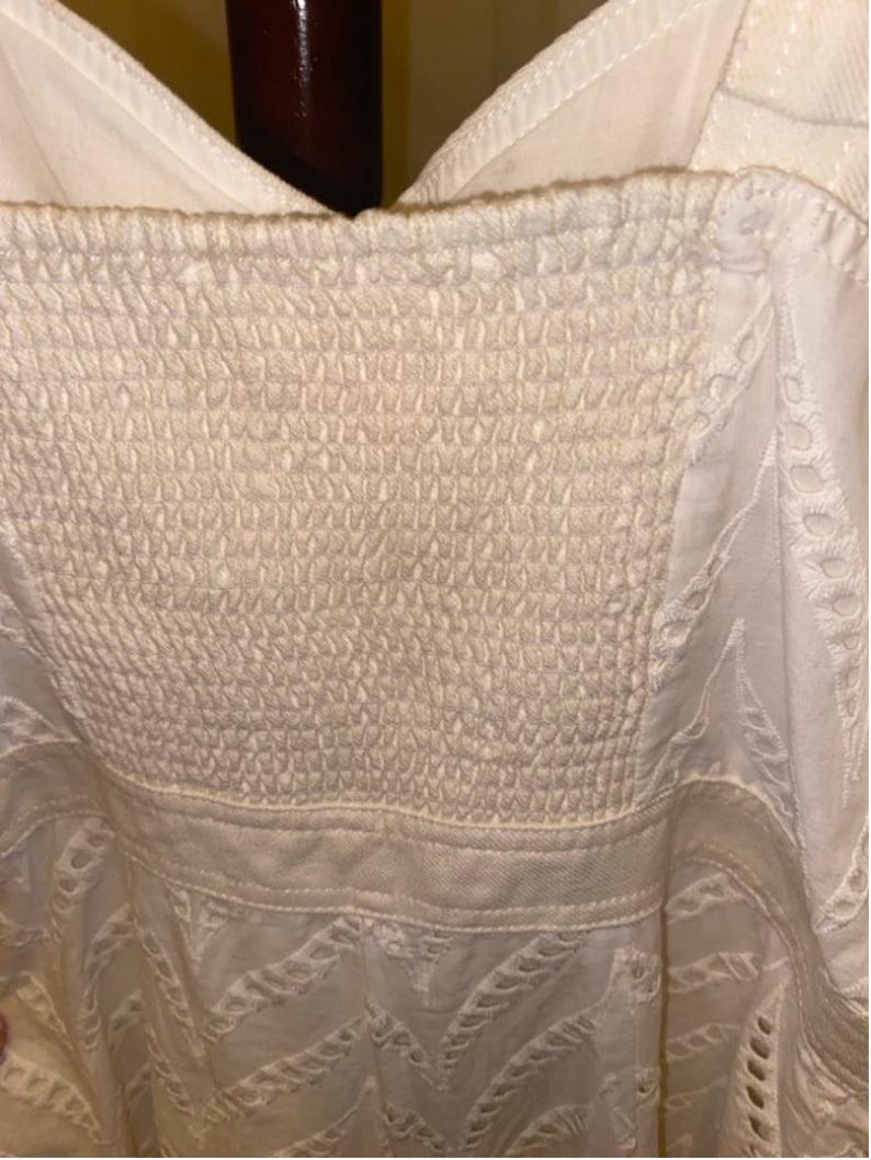 May include: White cotton dress with a white lace overlay and a smocked bodice.