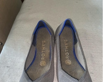May include: A pair of gray knit flats with a blue trim and a gold logo that says "ROTHYS".